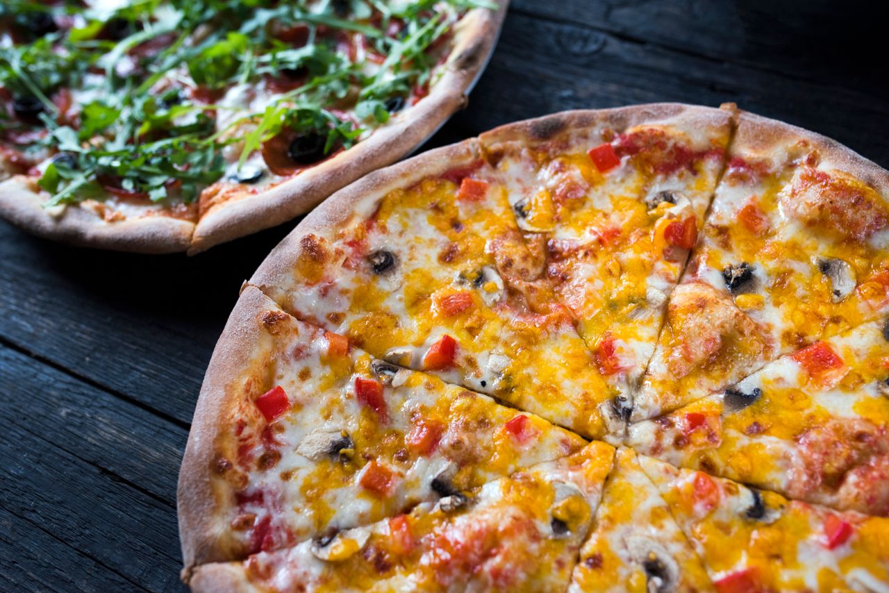 High angle of yummy pizzas with vegetable and mushroom slices on melted cheese on dark background